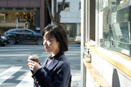 Young woman having a drink on the street cornerの写真素材