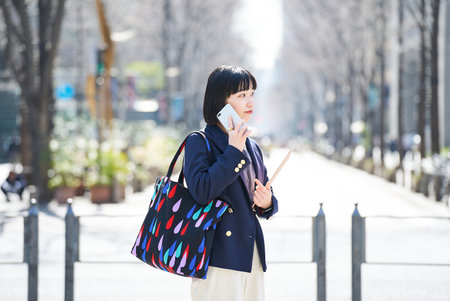 A woman talking on smartphone outdoorsの写真素材