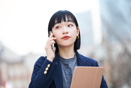 A woman talking on smartphone outdoorsの素材 [FY310201216210]