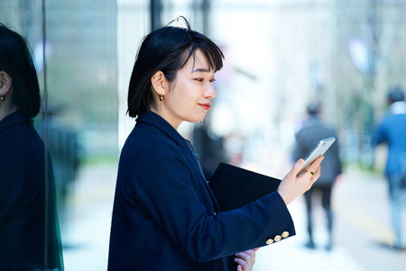 A woman looking at smartphone outdoorsの写真素材