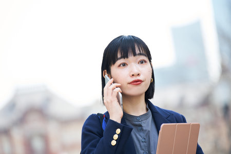 A woman talking on smartphone outdoorsの写真素材