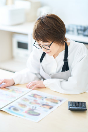 A woman wearing glasses looking at an advertising leaflet in the roomの写真素材