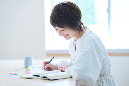 A woman in her thirties studying by text in the roomの写真素材