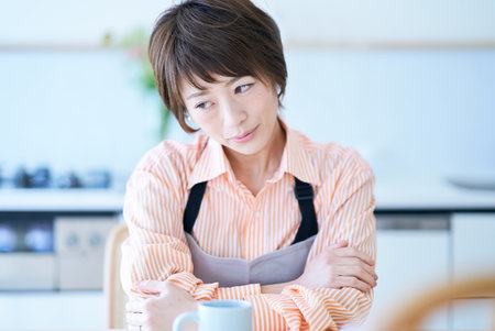A woman in an apron with a stressed expression in the roomの写真素材
