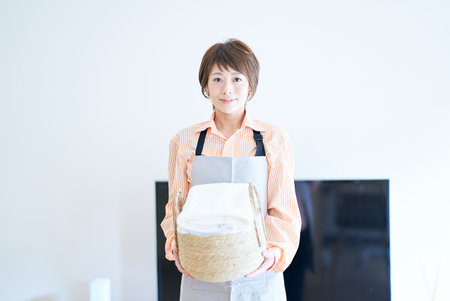 A woman in an apron with laundry in the roomの写真素材