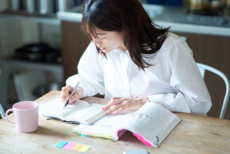 Adult woman studying with text at homeの写真素材