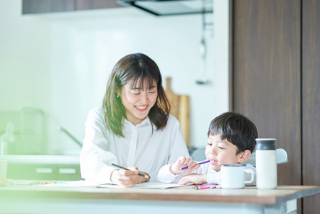 Mother and child studying with pencils and notebook in the roomの写真素材