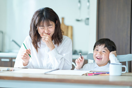 Mother and child studying with pencils and notebook in the roomの写真素材