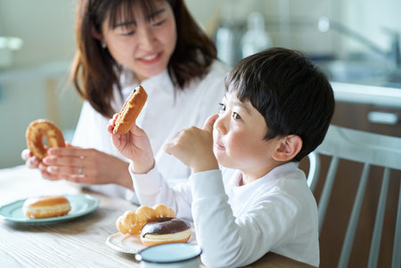 mother and son eating donut at homeの写真素材