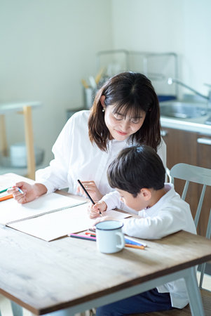 Mother and child studying with pencils and notebook in the roomの写真素材
