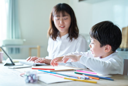 A mother working in her room and a child drawingの写真素材