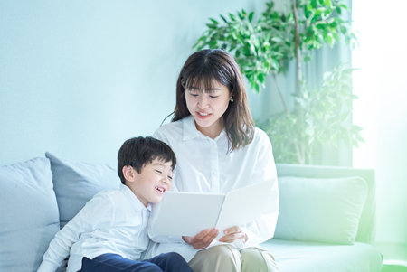 mother and boy sitting on the sofa and reading picture bookの写真素材
