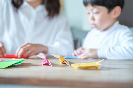 Parent and child playing with origami in the roomの写真素材