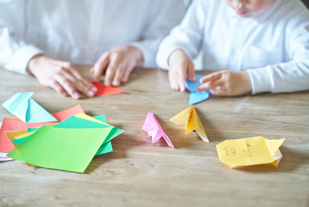 Parent and child playing with origami in the roomの写真素材