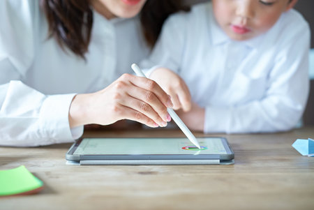 mother and child playing with a tablet PC in the roomの写真素材