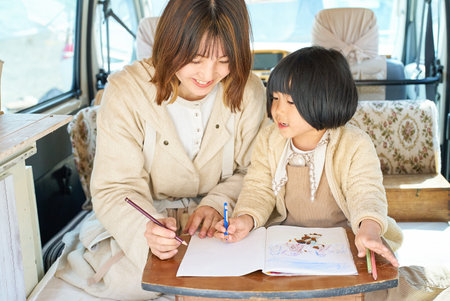 Mother and daughter enjoying drawing in a camperの写真素材