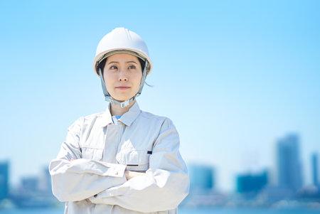 A woman wearing a helmet and wearing work clothes on fine dayの写真素材