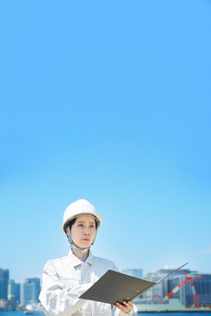 A woman in work clothes checking the site on fine dayの写真素材