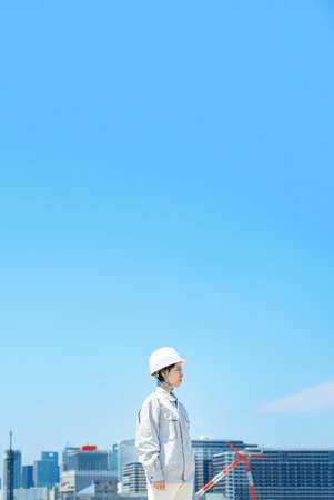 A woman wearing a helmet and wearing work clothes on fine dayの写真素材