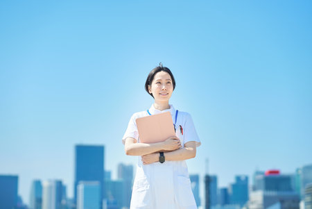 A woman in a white coat with a file outdoorsの写真素材