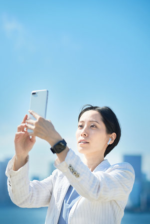 asian woman holding a smartphone outdoorsの写真素材