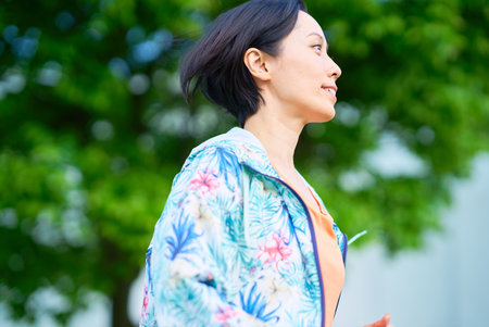 Asian woman running on urban green space