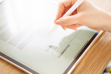 Hand of a woman who makes an electronic signature with a stylus pen