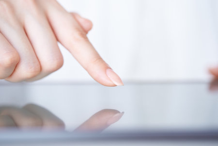 The hand of a woman who touches and operates the screen of a tablet PC