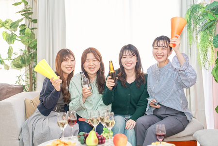 Four young women watching sports indoorsの写真素材