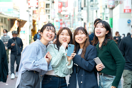 Young women happily using smartphones in the cityの写真素材
