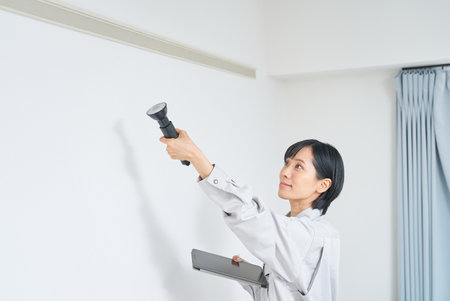 A woman in work clothes checking the condition of a house wallの写真素材