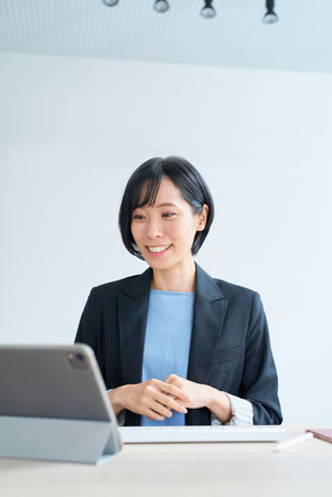 Businesswoman using tablet pc for online communication in the roomの写真素材