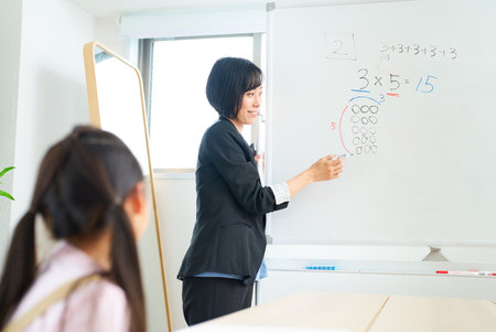 A woman in a suit teaching a child in the roomの写真素材