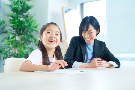 A girl studying and a woman in a suit to support in the roomの写真素材