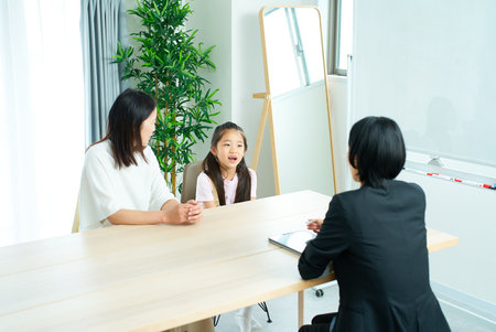 Conversation scene of a woman in a suit with a parent and child in the roomの写真素材
