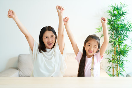 Parent and child who are happy to raise both hands in the roomの写真素材