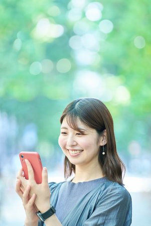 Young woman looking at smartphone screen on fine dayの写真素材