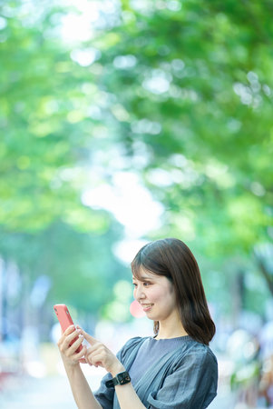 Young woman looking at smartphone screen on fine dayの写真素材