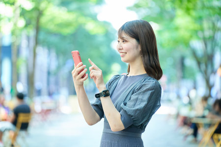 Young woman looking at smartphone screen on fine dayの写真素材