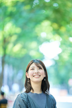 smiling woman portrait at greenful street on fine dayの写真素材