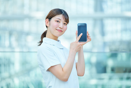 A woman in a white coat holding a digital device indoorsの写真素材