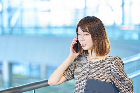Young businesswoman talking on smartphone in the buildingの写真素材