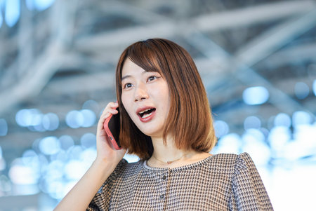 Young businesswoman talking on smartphone in the buildingの写真素材