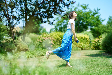 Woman relaxing in green space on fine dayの写真素材