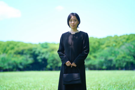 A woman in mourning clothes standing in a green spaceの写真素材