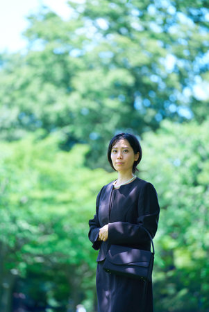 A woman in mourning clothes standing in a green spaceの写真素材