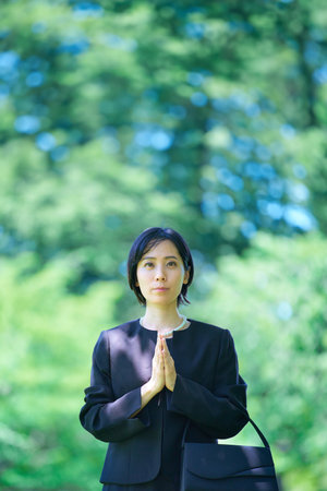 A woman who puts her hands together in a mourning dress outdoorsの写真素材