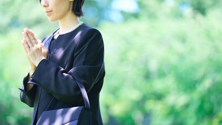 A woman who puts her hands together in a mourning dress outdoorsの写真素材
