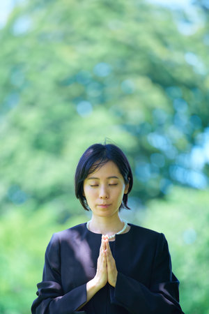 A woman who puts her hands together in a mourning dress outdoorsの写真素材