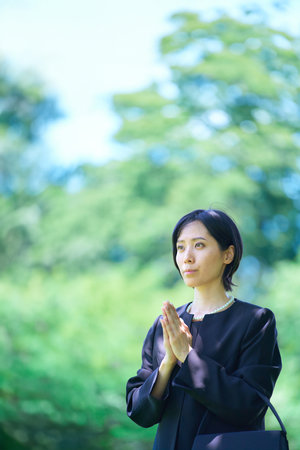 A woman who puts her hands together in a mourning dress outdoorsの写真素材